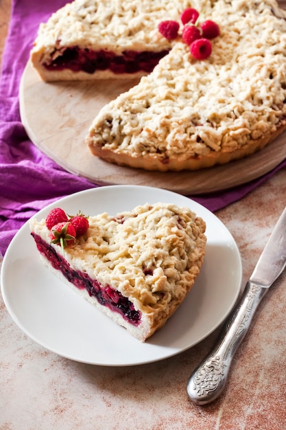 Homemade berry shortcrust pie with crumble on wooden board