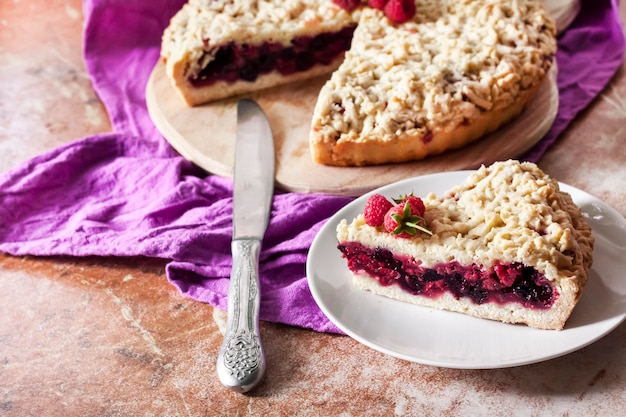 Homemade berry shortcrust pie with crumble on wooden board