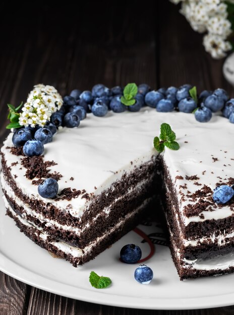 Homemade bird cherry cake with sour cream, decorated with blueberries and mint leaves on baking paper