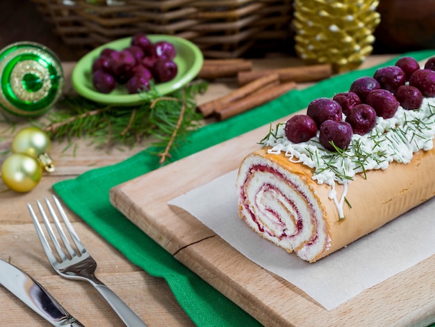 Homemade biscuit cherry roll with yoghurt cream and Christmas decoration rustic style