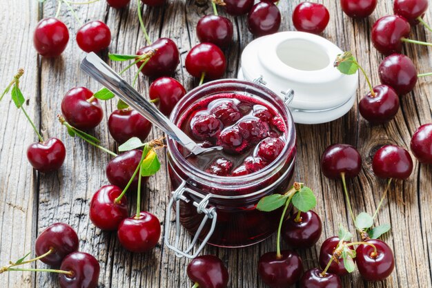 Homemade black cherry jam in the jar on wooden wall,selective focus