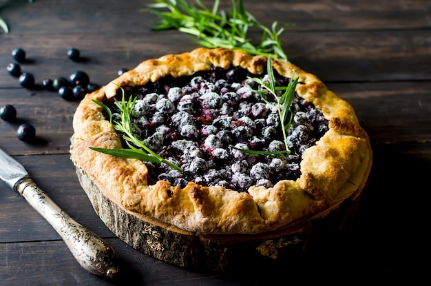 Homemade blackcurrant galette on old dark wooden background