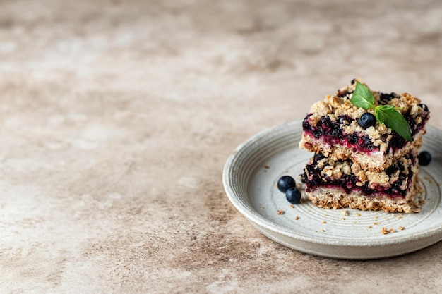 Homemade blueberry crumble bars on a plate decorated with mint on beige background. text space