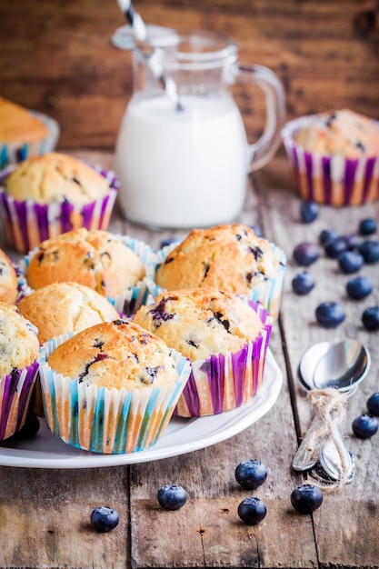 Homemade blueberry muffins with milk on a rustic wooden background