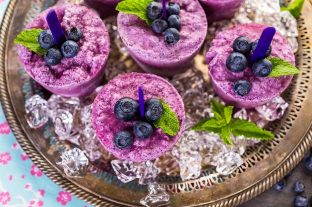 Homemade blueberry popsicles made in plastic cups.