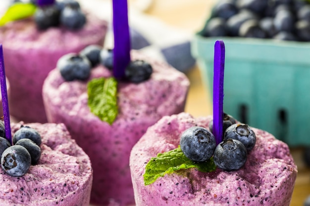 Photo homemade blueberry popsicles made in plastic cups.