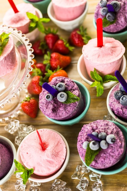 Homemade blueberry and strawberry popsicles made in plastic cups.