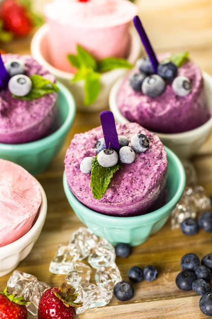 Homemade blueberry and strawberry popsicles made in plastic cups.