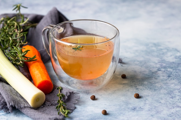 Homemade bone broth in glass mug and vegetables