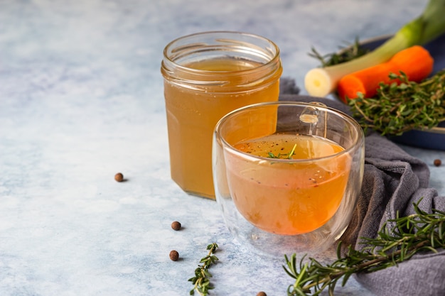 Homemade bone broth in glass mug and vegetables