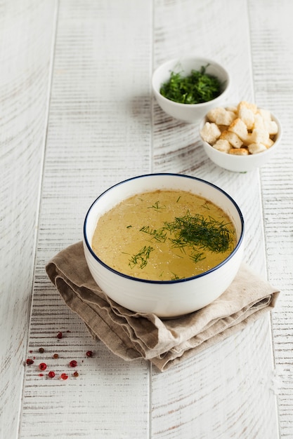 Photo homemade bone broth in a white bowl on a wooden table. the concept of healthy eating.