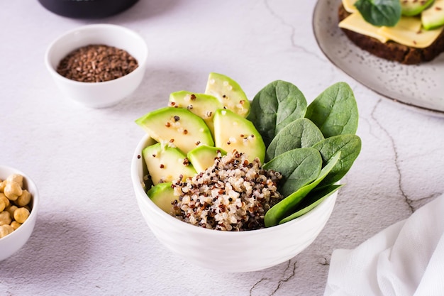 Ciotola fatta in casa con quinoa di avocado e spinaci sul tavolo nutrizione vitaminica sana