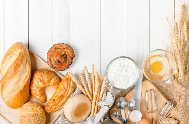 Homemade bread or bakery with fresh egg, flour and bakery equipment on white wood background