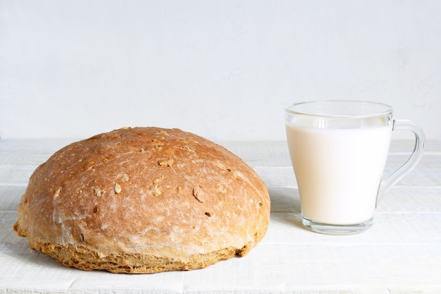 Homemade bread and cup of milk on white rustic wooden table