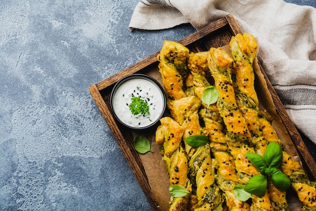 Homemade bread sticks with cheese, pesto sauce and black sesame seeds on gray stone vintage surface