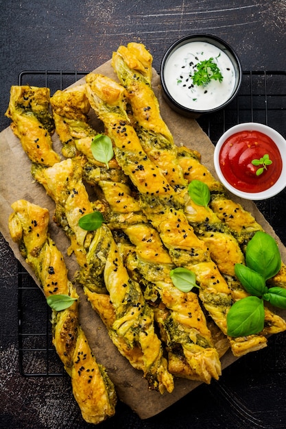 Homemade bread sticks with cheese, pesto sauce and black sesame seeds on gray stone vintage surface