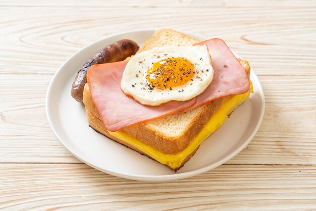 homemade bread toasted cheese topped ham and fried egg with pork sausage for breakfast