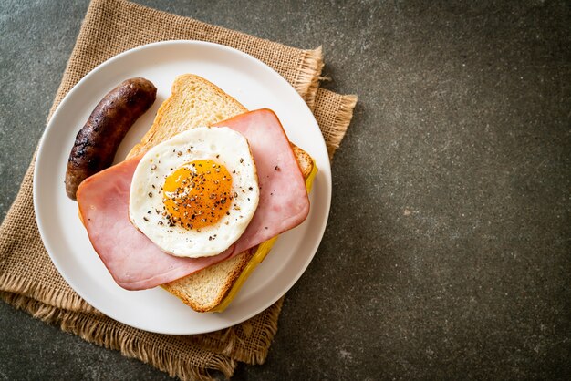 homemade bread toasted cheese topped ham and fried egg with pork sausage for breakfast