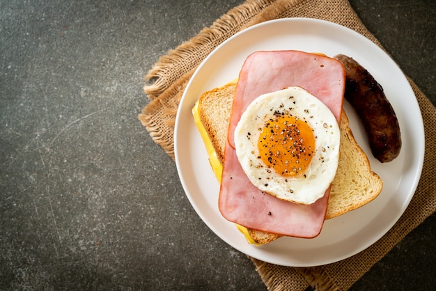 homemade bread toasted cheese topped ham and fried egg with pork sausage for breakfast