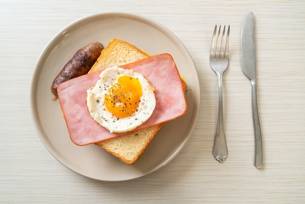 homemade bread toasted cheese topped ham and fried egg with pork sausage for breakfast