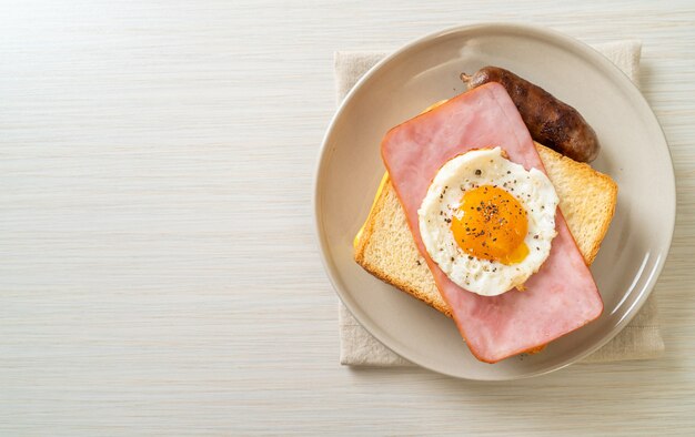 homemade bread toasted cheese topped ham and fried egg with pork sausage for breakfast