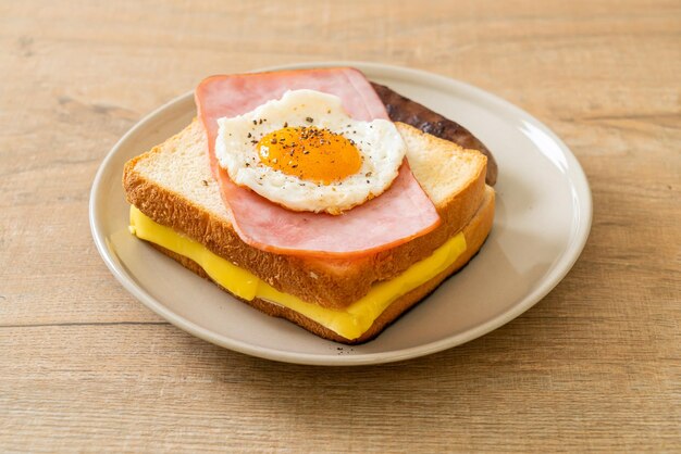 homemade bread toasted cheese topped ham and fried egg with pork sausage for breakfast