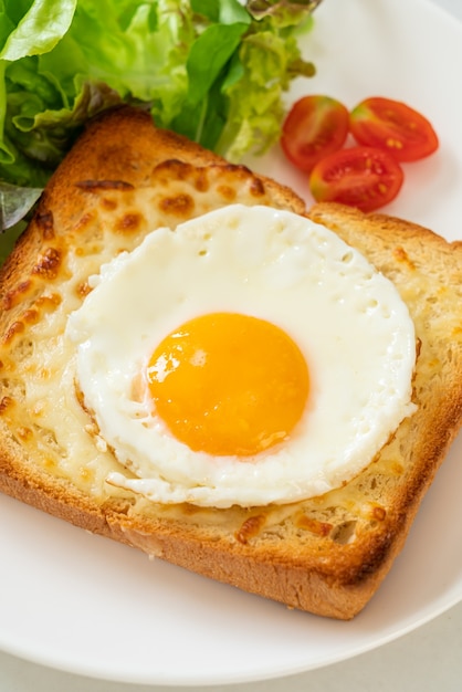 Homemade bread toasted with cheese and fried egg on top with\
vegetable salad for breakfast