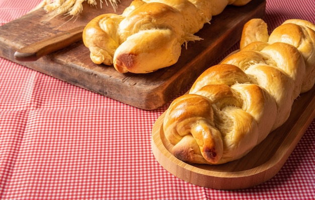 自家製のパン、木のひだの形をした2つのパン、赤と白の市松模様のテーブルクロス、ナイフ、小麦の枝。