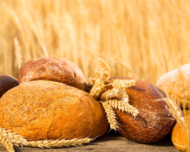 Homemade bread and wheat on the wooden table in autumn field