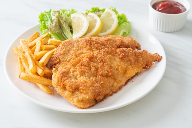 Homemade breaded weiner schnitzel with potato chips - fried\
chicken with french fries - european food style