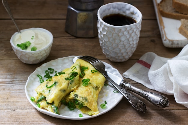 Homemade breakfast of omelet with asparagus and onions and hot coffee. Rustic style.