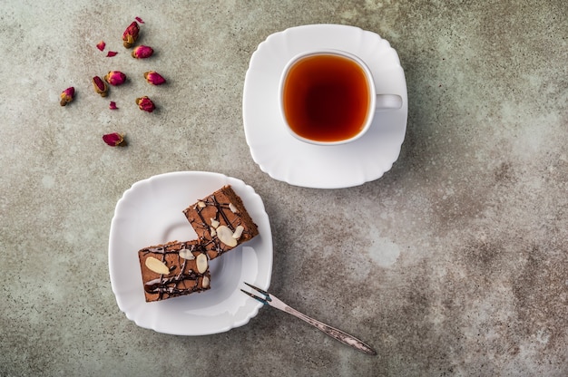 Homemade brownie with almonds on a saucer with a fork on wooden table.