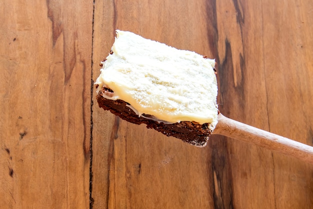 Photo homemade brownie with icing on wooden background.