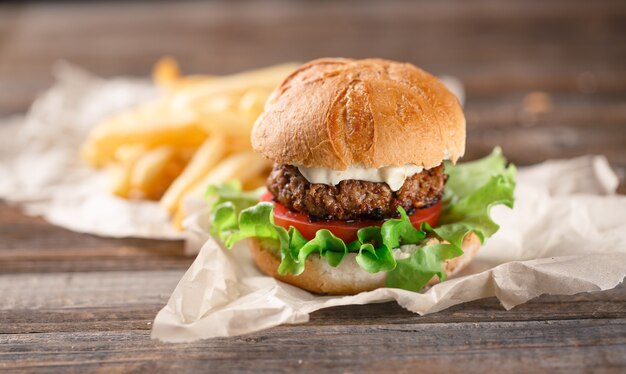 Homemade burger with french fries on wooden table