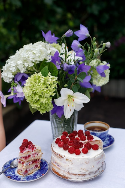 Homemade cake and a bouquet of flowers on a table in a summer garden