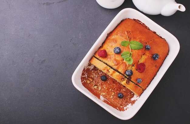 Homemade cake decorated with raspberries and blueberries on a black background