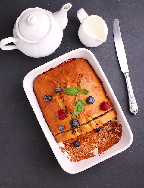 Homemade cake decorated with raspberries and blueberries on a black background