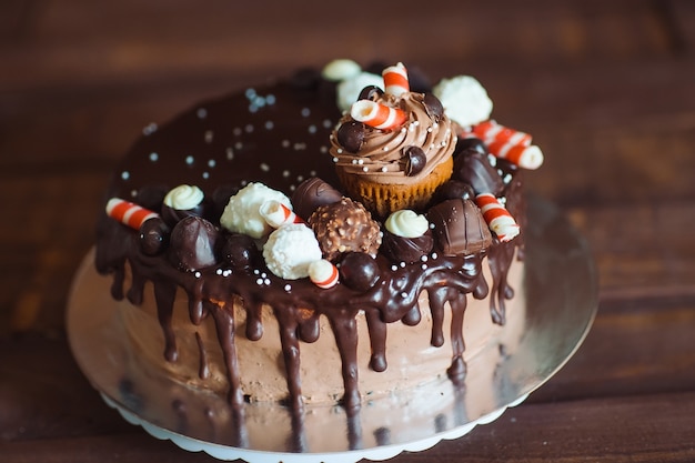 Homemade cake decorated with sweets, cupcakes and waffles.