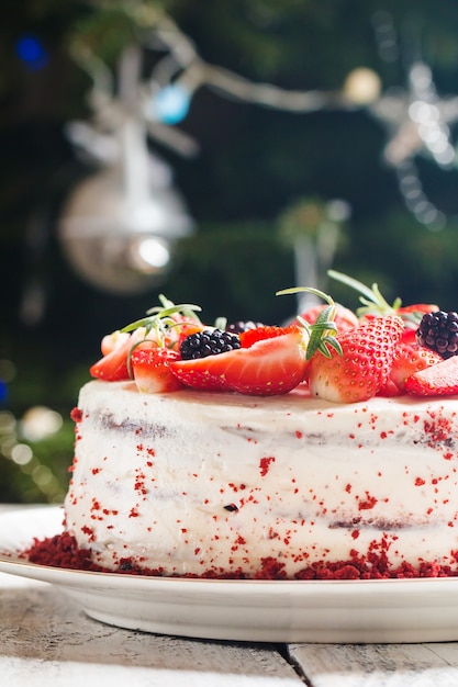 Torta casalinga red velvet decorata con crema e frutti di bosco sulla superficie di natale