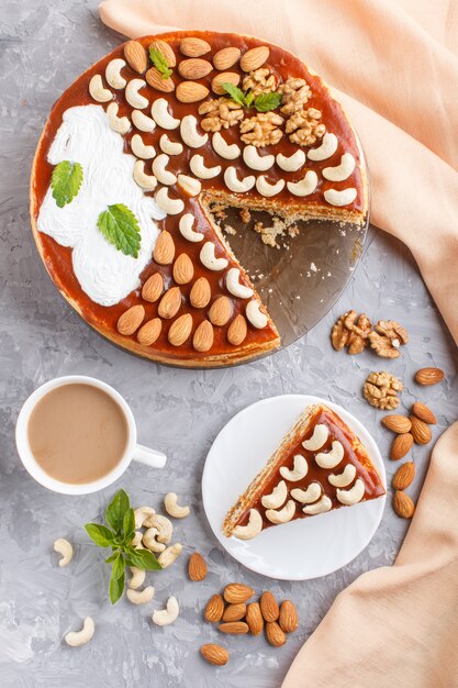 Torta fatta in casa con crema al caramello e noci con una tazza di caffè sul cemento grigio