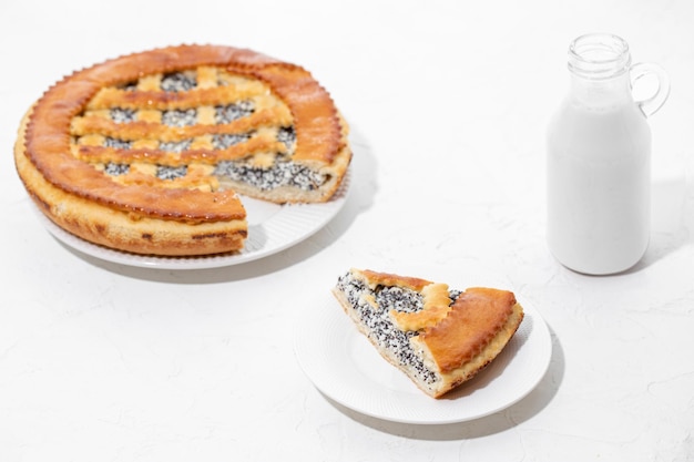 Homemade cake with cottage cheese and poppy seeds with a bottle of milk on a white table