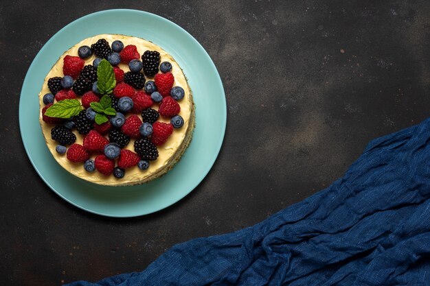 Torta fatta in casa con frutti di bosco freschi su sfondo scuro.