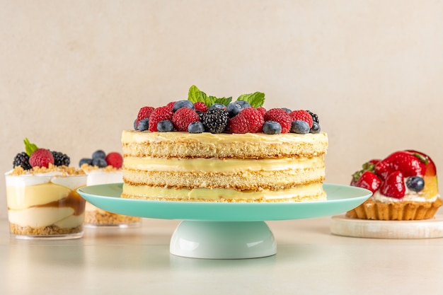 Homemade cake with fresh berries and sweet desserts on table.