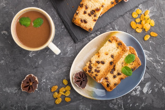 Homemade cake with raisins, dried persimmon and a cup of hot chocolate on a black concrete background. top view, flat lay, copy space.