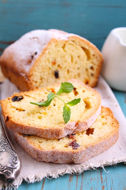 Homemade cake with raisins and nuts cut into pieces on a blue background