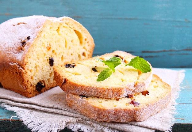 Homemade cake with raisins and nuts cut into pieces on a blue background