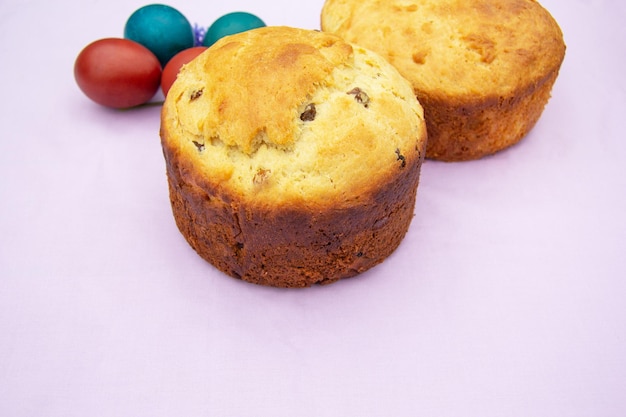 Homemade cakes are on a pink napkin painted eggs lie nearby