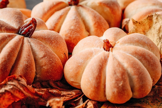 Homemade cakes in the shape of pumpkin with autumn leaves close up. Halloween sweets concept