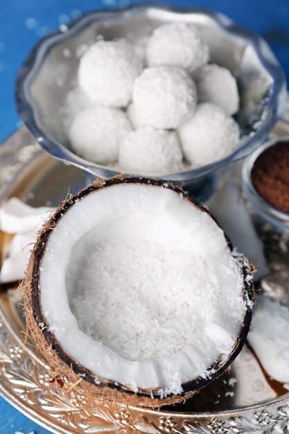 Homemade candies in coconut flakes and ingredients on color wooden