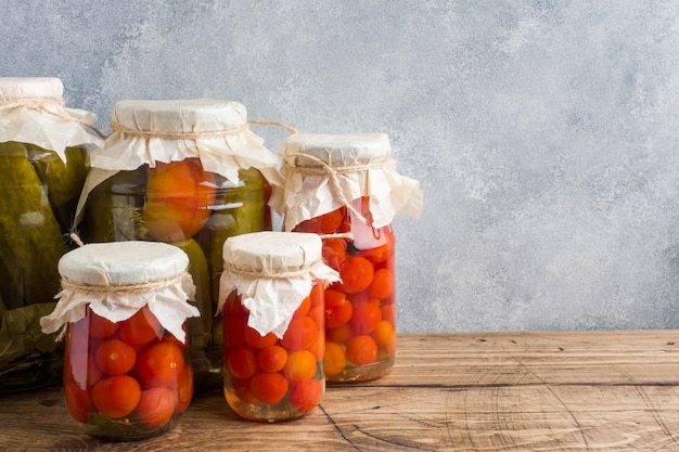 Homemade canned vegetables in cans. Pickled tomatoes and cucumbers in a rural style.